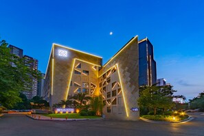 A modern hotel with a distinctive geometric facade and illuminated signage. - SSAW Boutique Hotel Liuzhou Garden (Liuzhou)