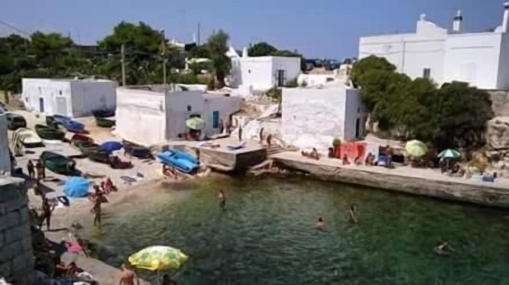 Une ville côtière dotée d’un plan d’eau central, de bâtiments blancs et où les habitants pratiquent diverses activités nautiques.