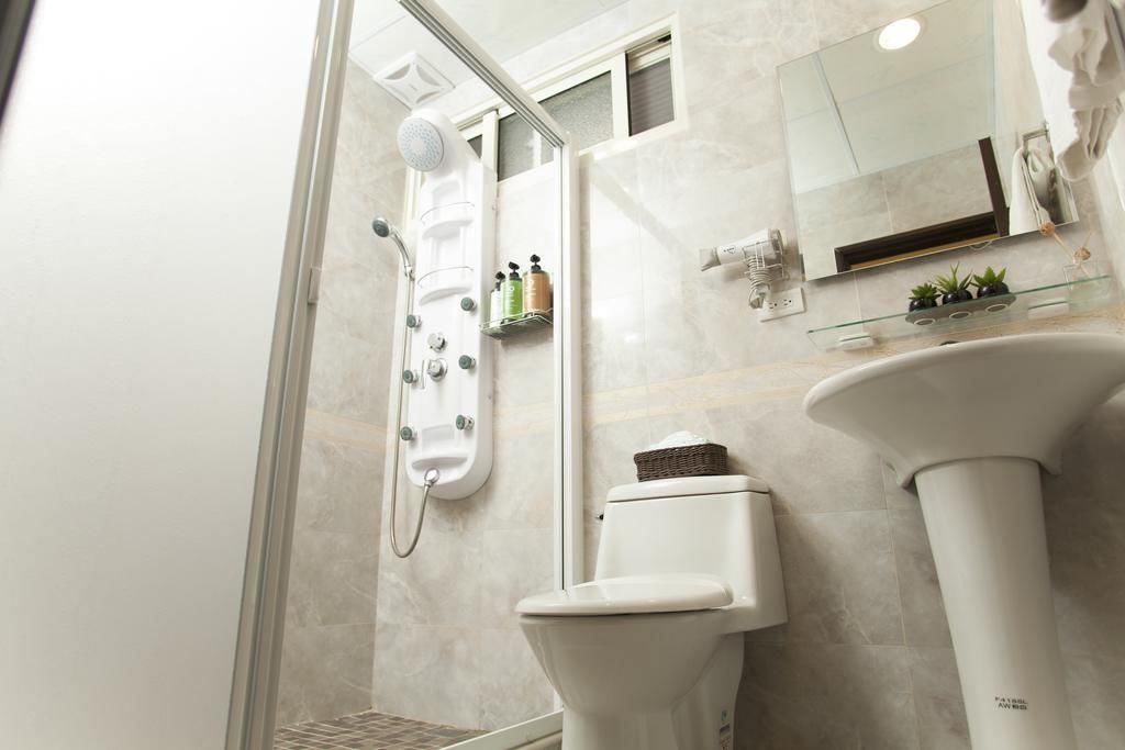 A modern bathroom with a glass shower enclosure, a toilet, and a sink with a mirror above it.
