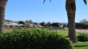 Un resort con palmeras, un parque infantil y vista al mar.