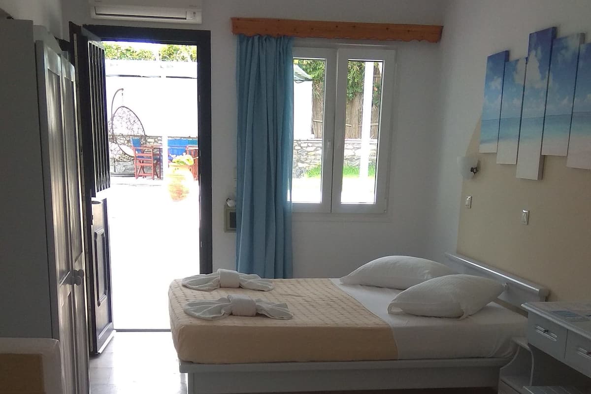 A bedroom with a bed, a bedside table, a wardrobe, and a window with curtains.