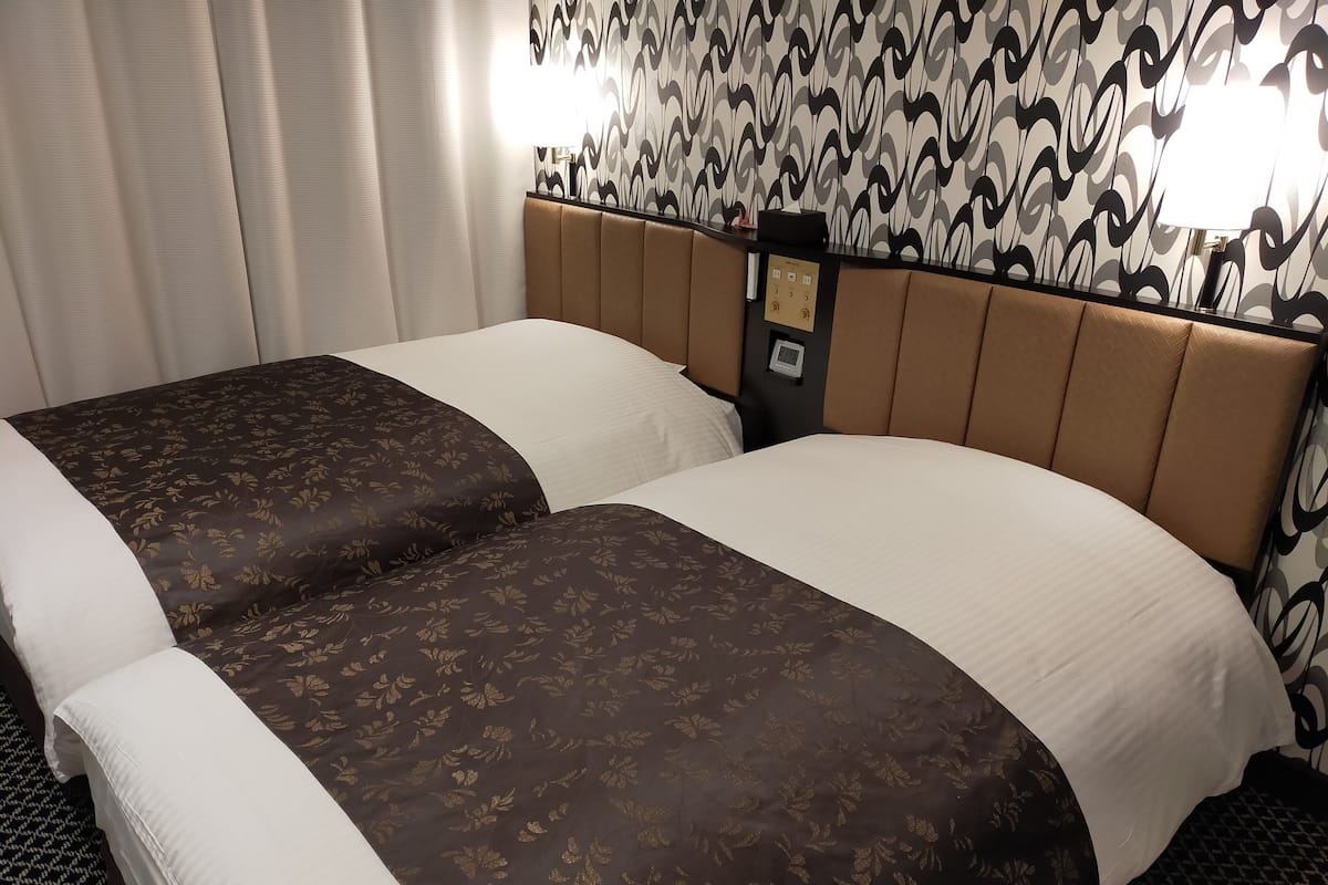 A double bed with a headboard, a control panel, and a patterned wall.