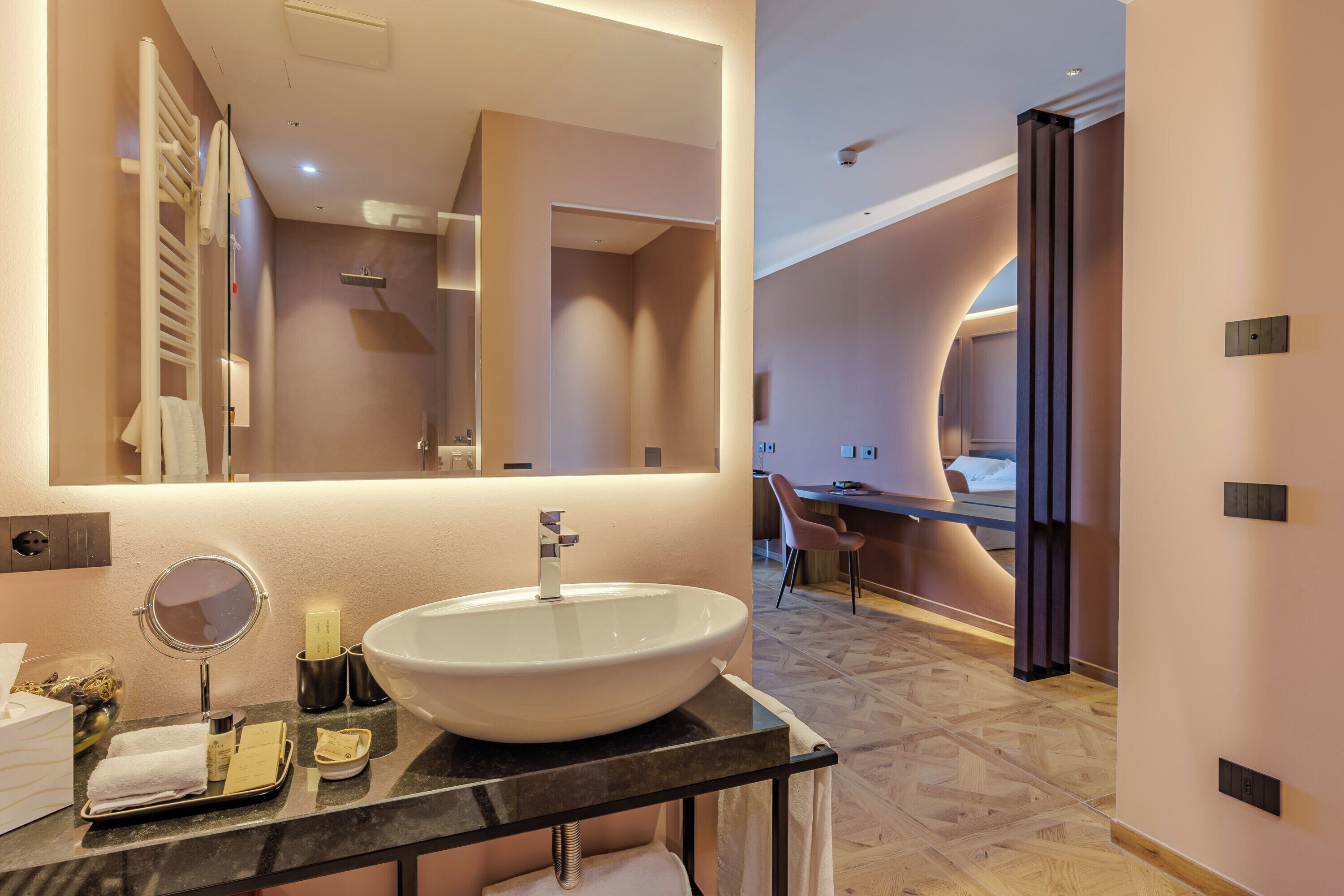 A modern bathroom with a large mirror, a white sink, and a towel rack.