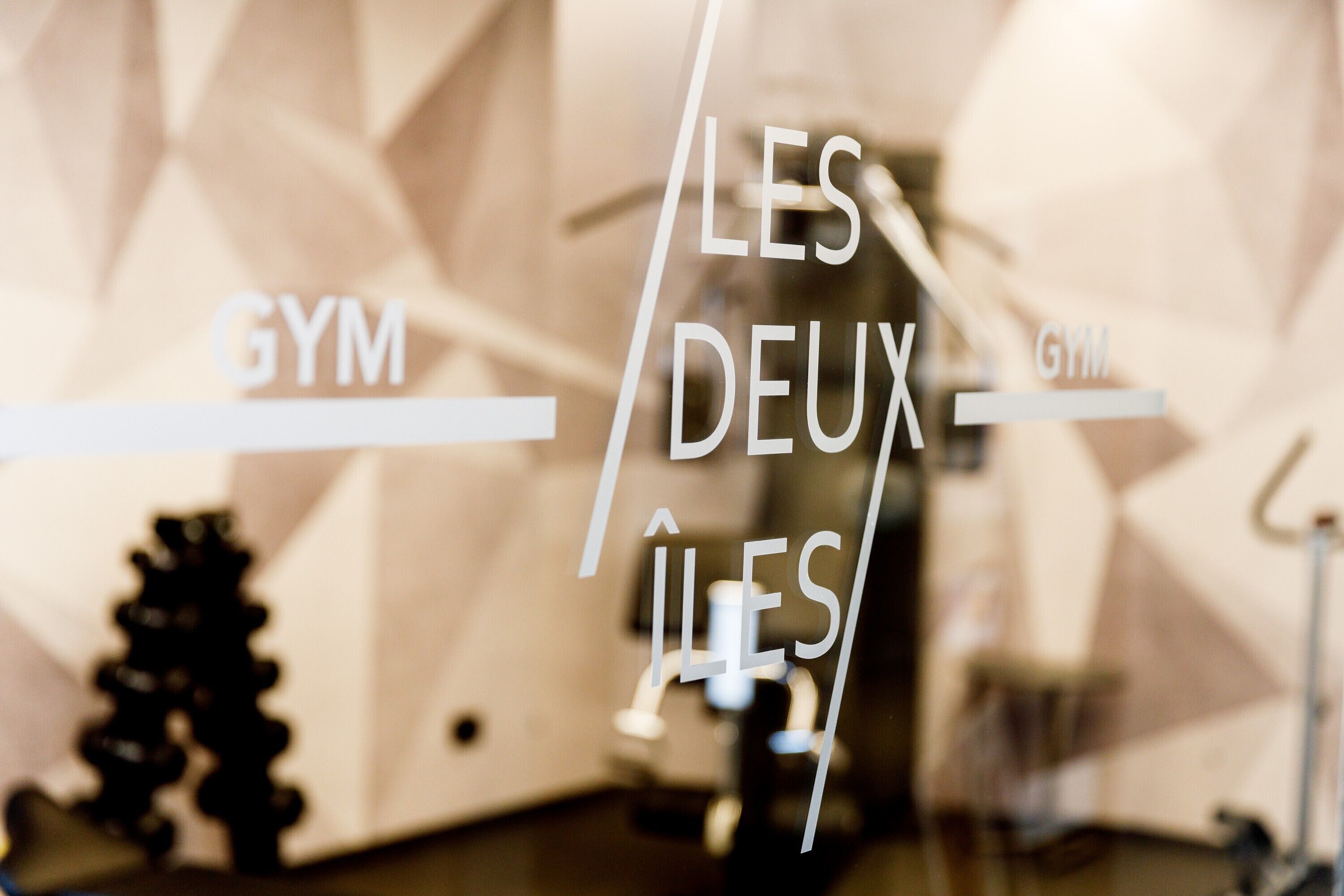 A gym with mirrored walls and exercise equipment.