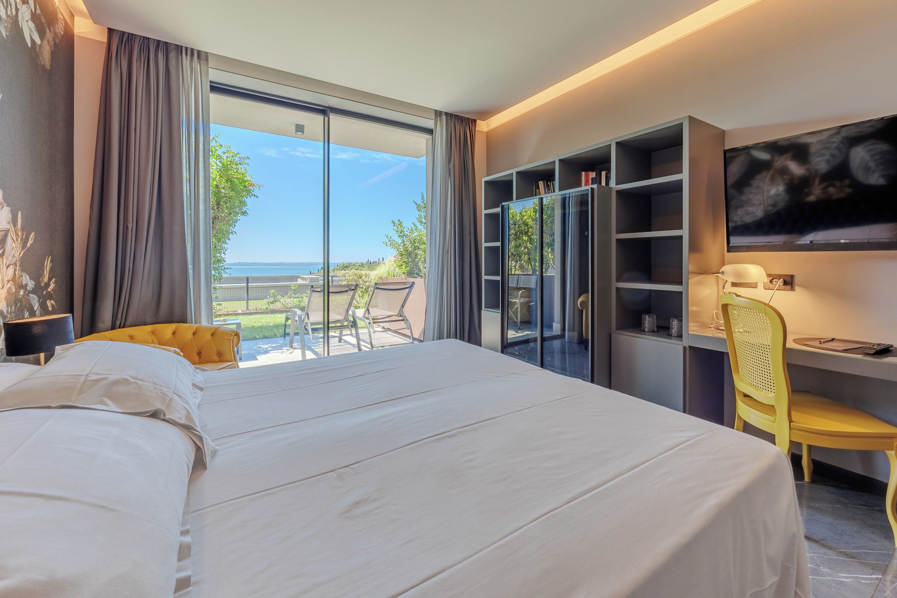 Un dormitorio con una cama grande, un escritorio con silla, una estantería y un televisor.