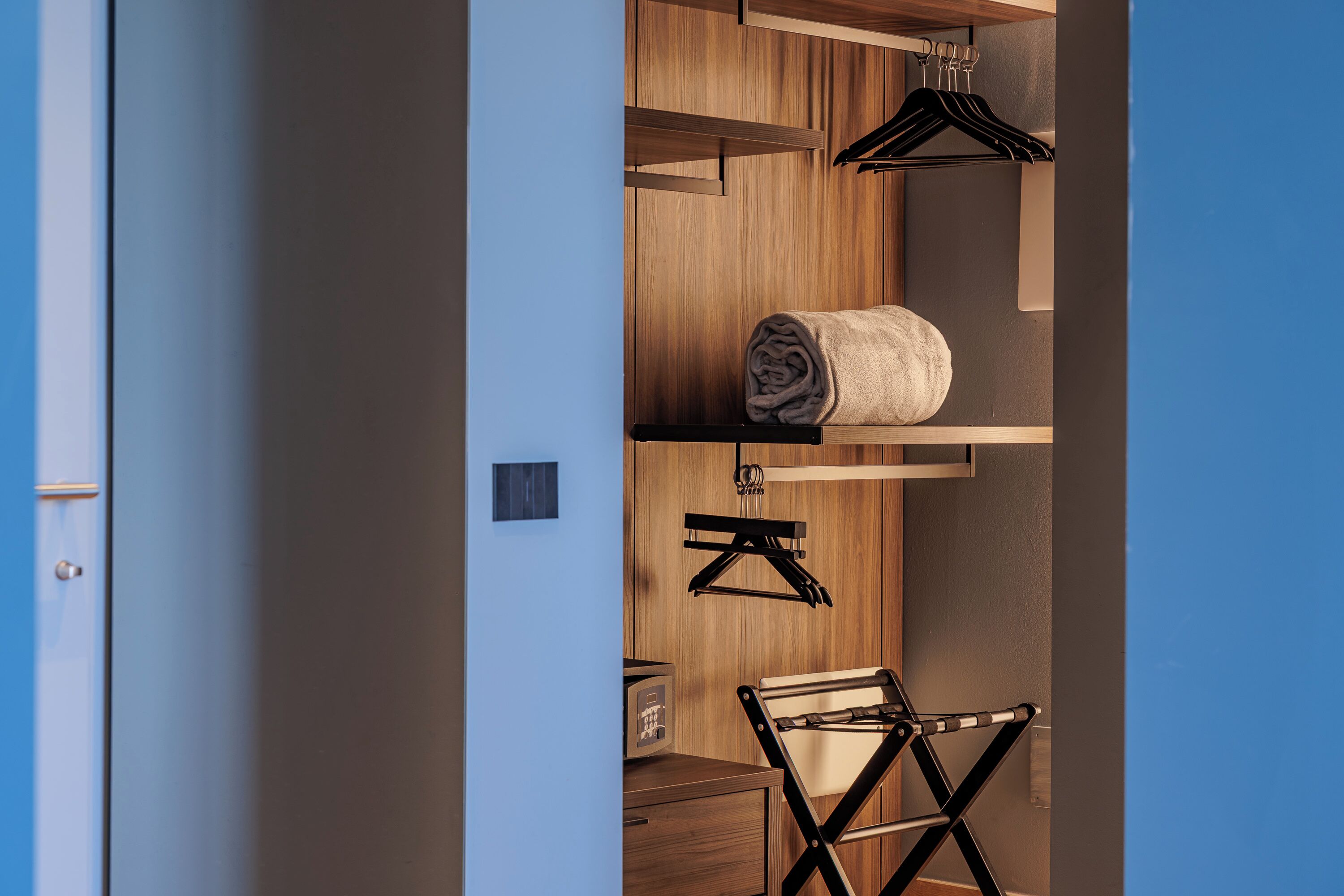 A modern room with a wooden wardrobe, a hanging rack, and a compact folding chair.
