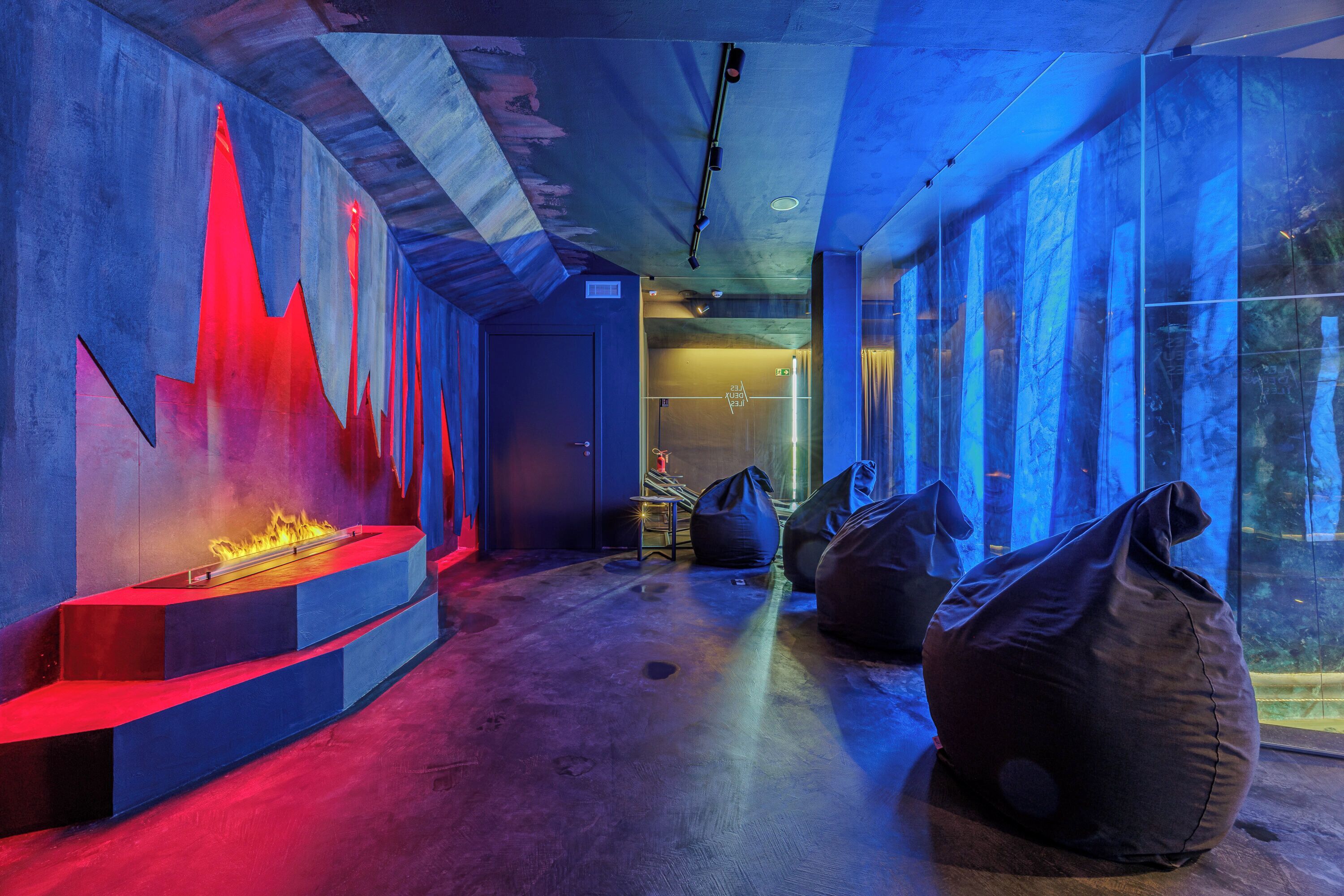 A modern interior with a fire feature, bean bags, and large windows.