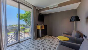 Une chambre d’hôtel moderne dotée d’une grande porte-fenêtre coulissante donnant sur un espace extérieur, d’un canapé, d’une petite table jaune et d’une lampe noire.