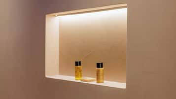 A bathroom with a shelf containing two bottles and a bar of soap.