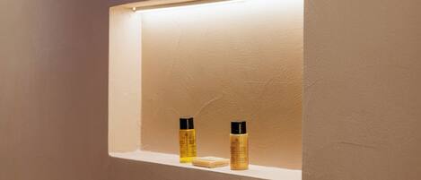 A bathroom with a shelf containing two bottles and a bar of soap.