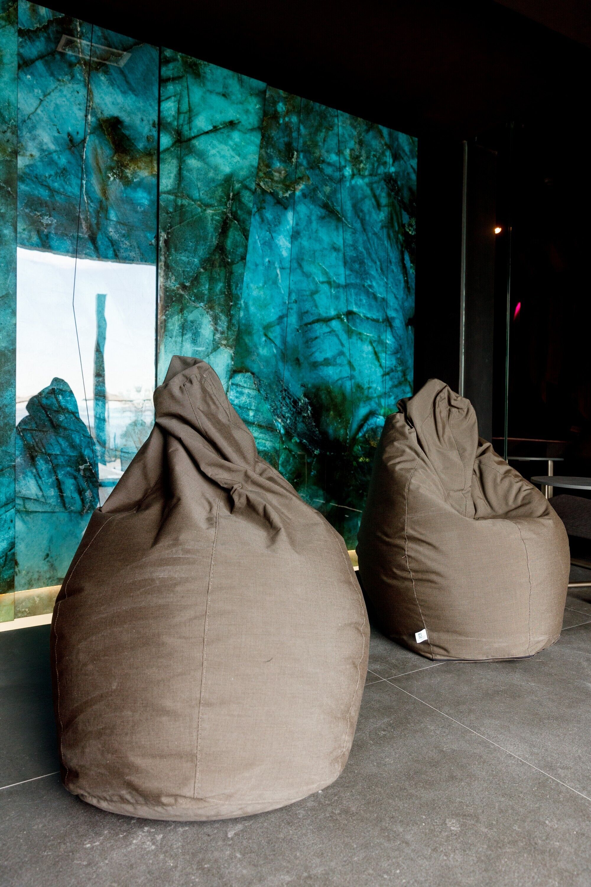 Deux fauteuils en forme de sac de haricots dans une pièce moderne, avec une grande fresque abstraite sur le mur.