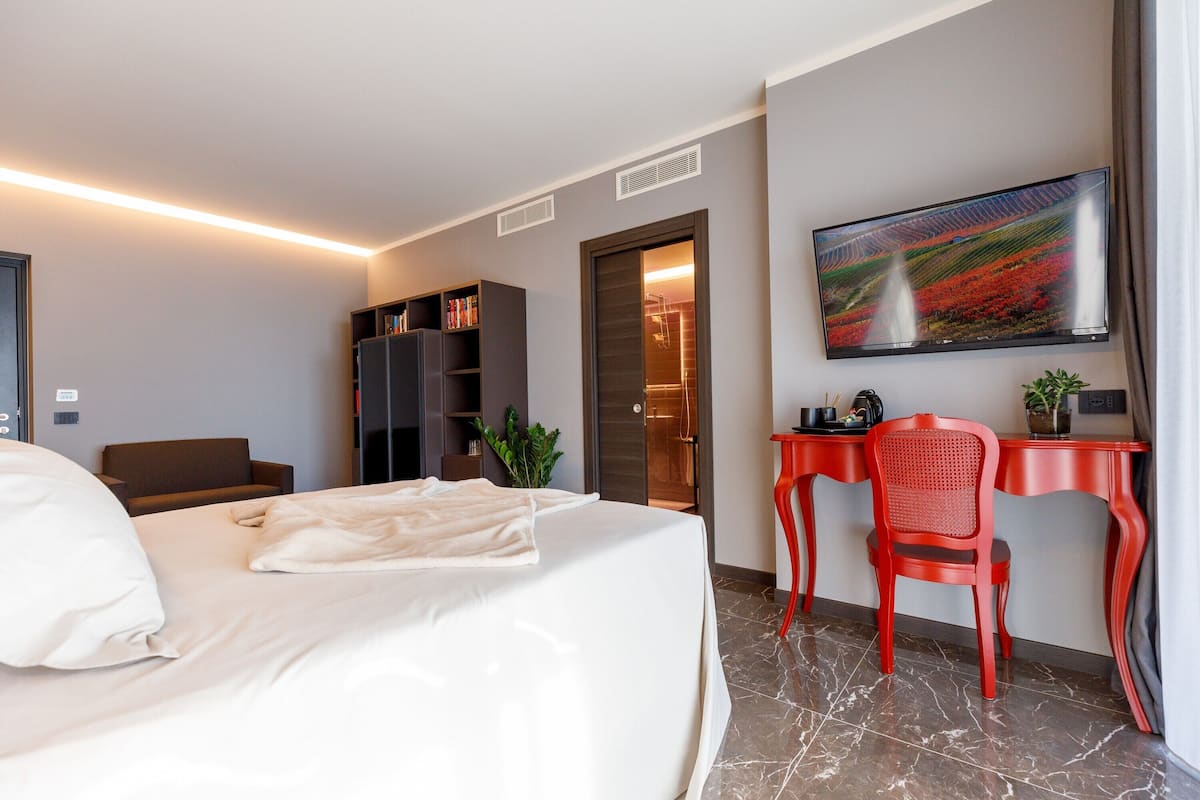 Una habitación de hotel moderna con una cama, un escritorio, una silla, un televisor y una estantería.