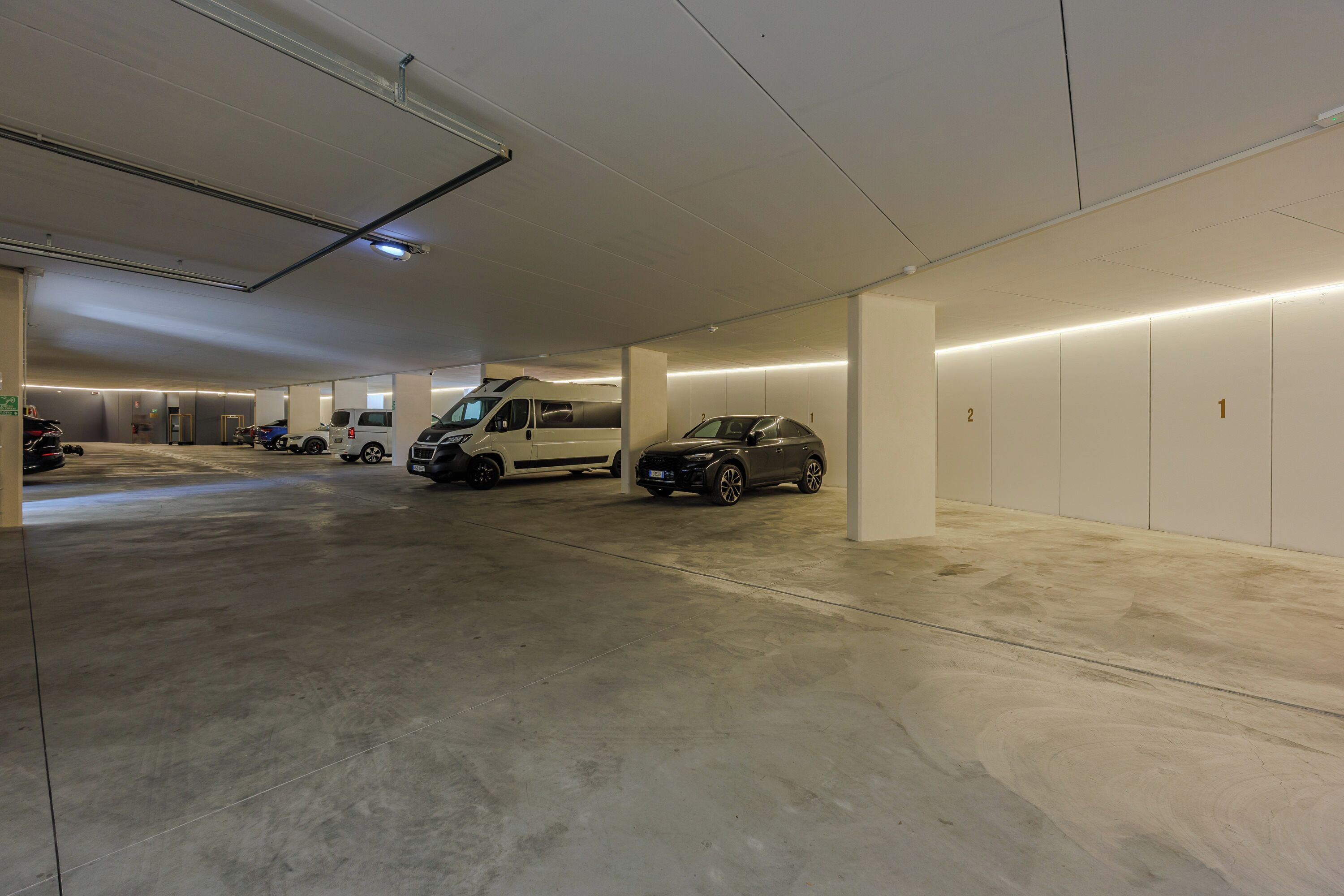 Ett parkeringshus med flera våningsplan där det står flera bilar och en skåpbil.