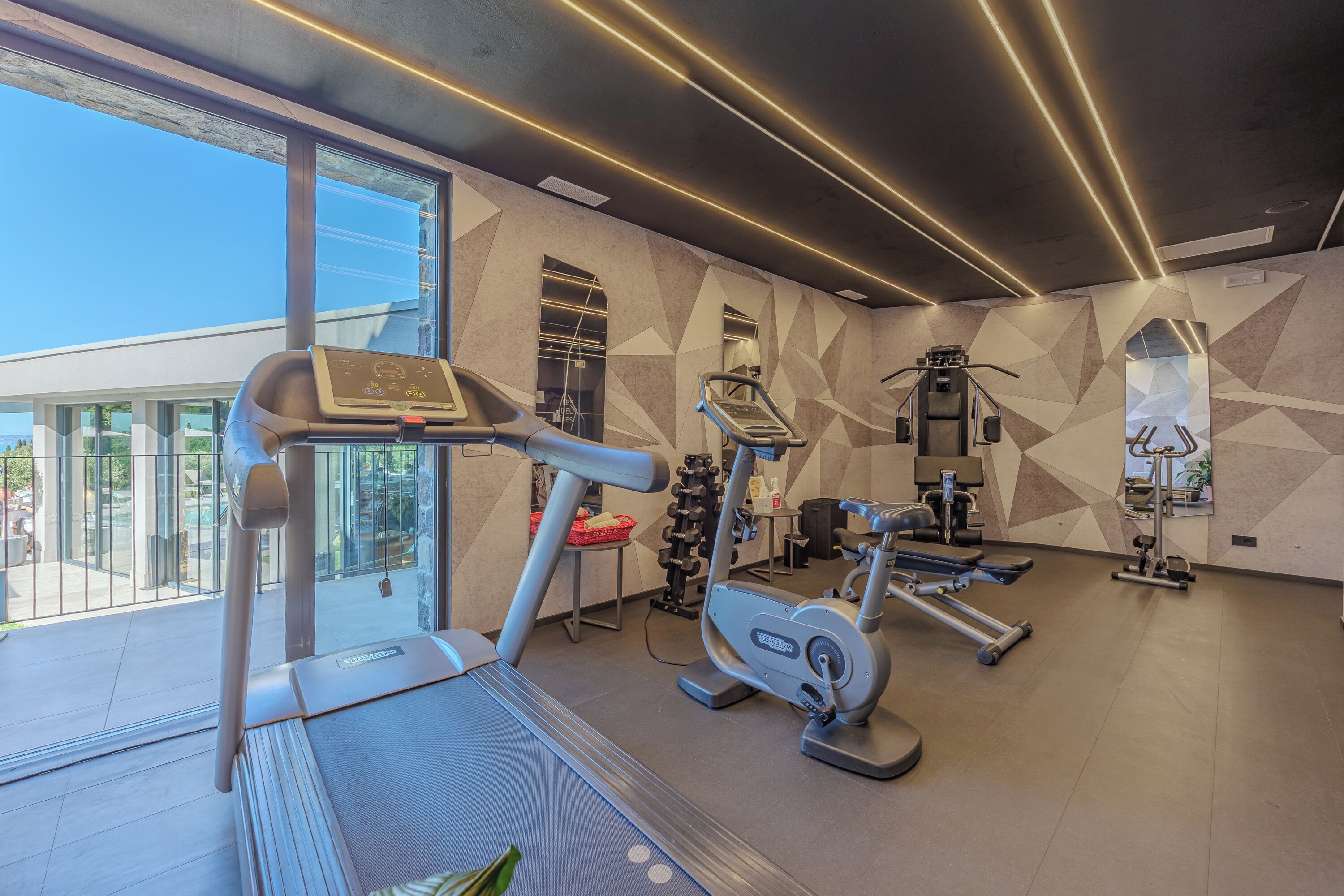 A modern gym with a treadmill, elliptical, and weight machines.