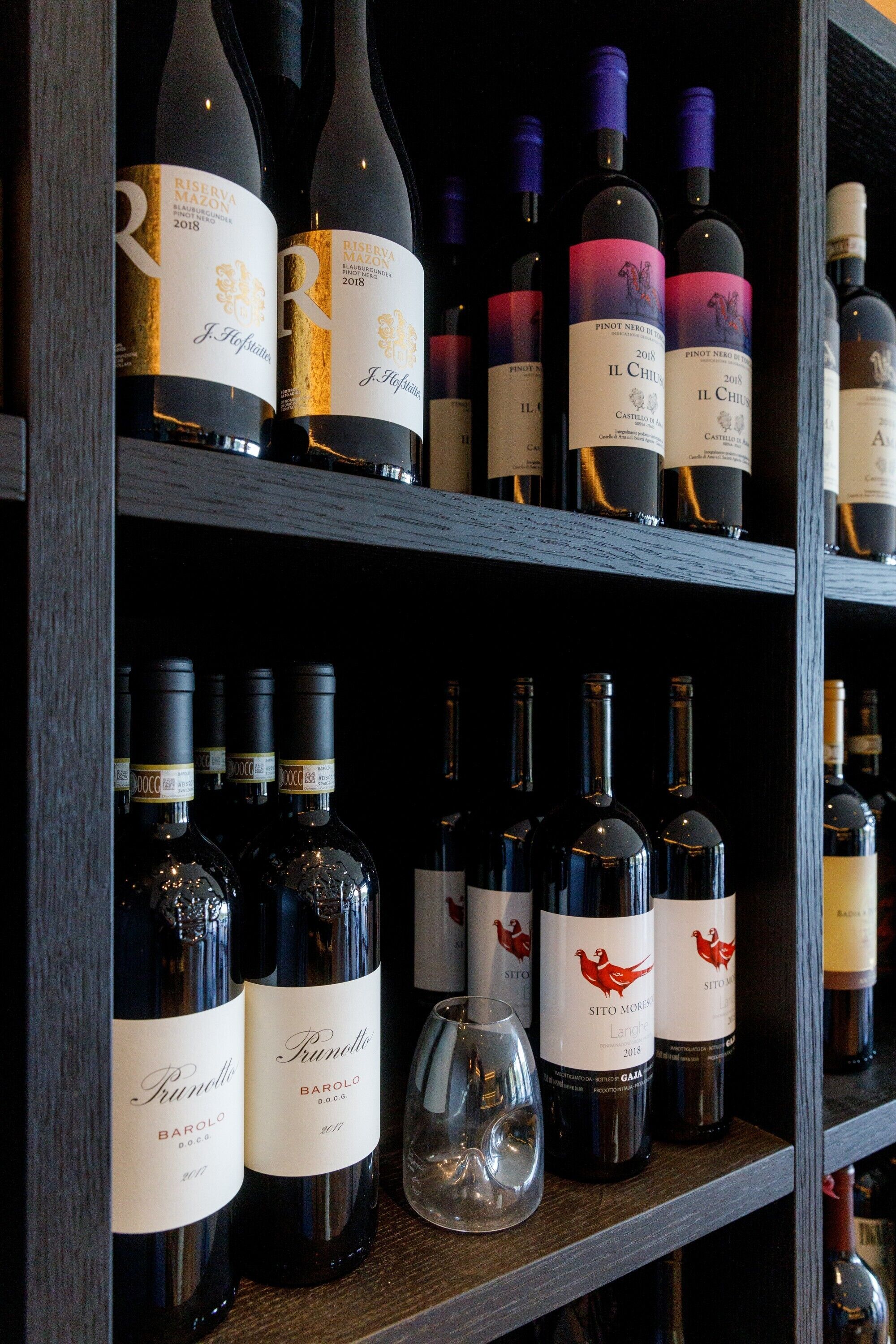 Un meuble à bouteilles contenant différentes sortes de vins, notamment des marques comme Riserva Mazon et Sitomores.