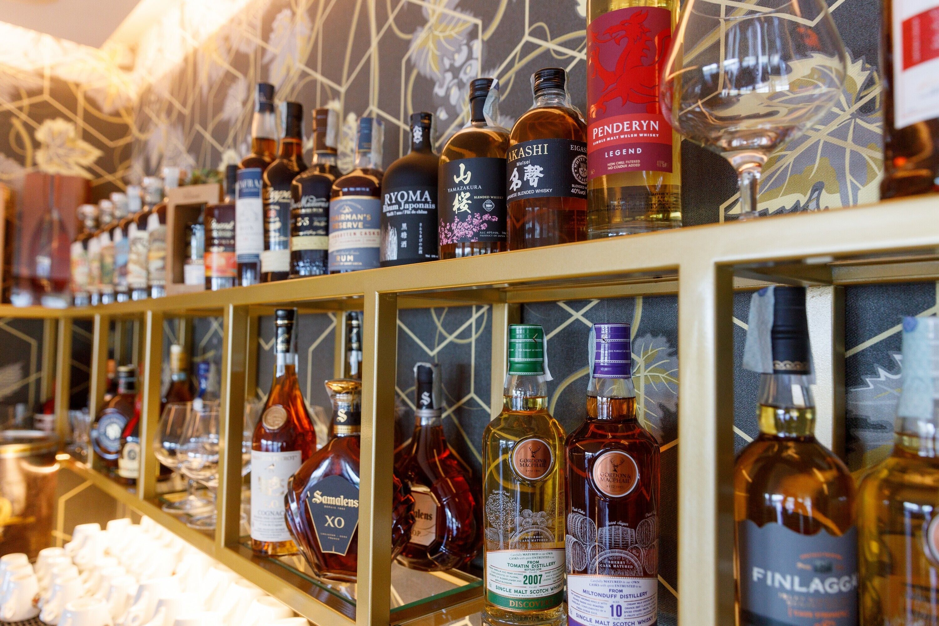 A variety of liquor bottles displayed on shelves in a bar setting.