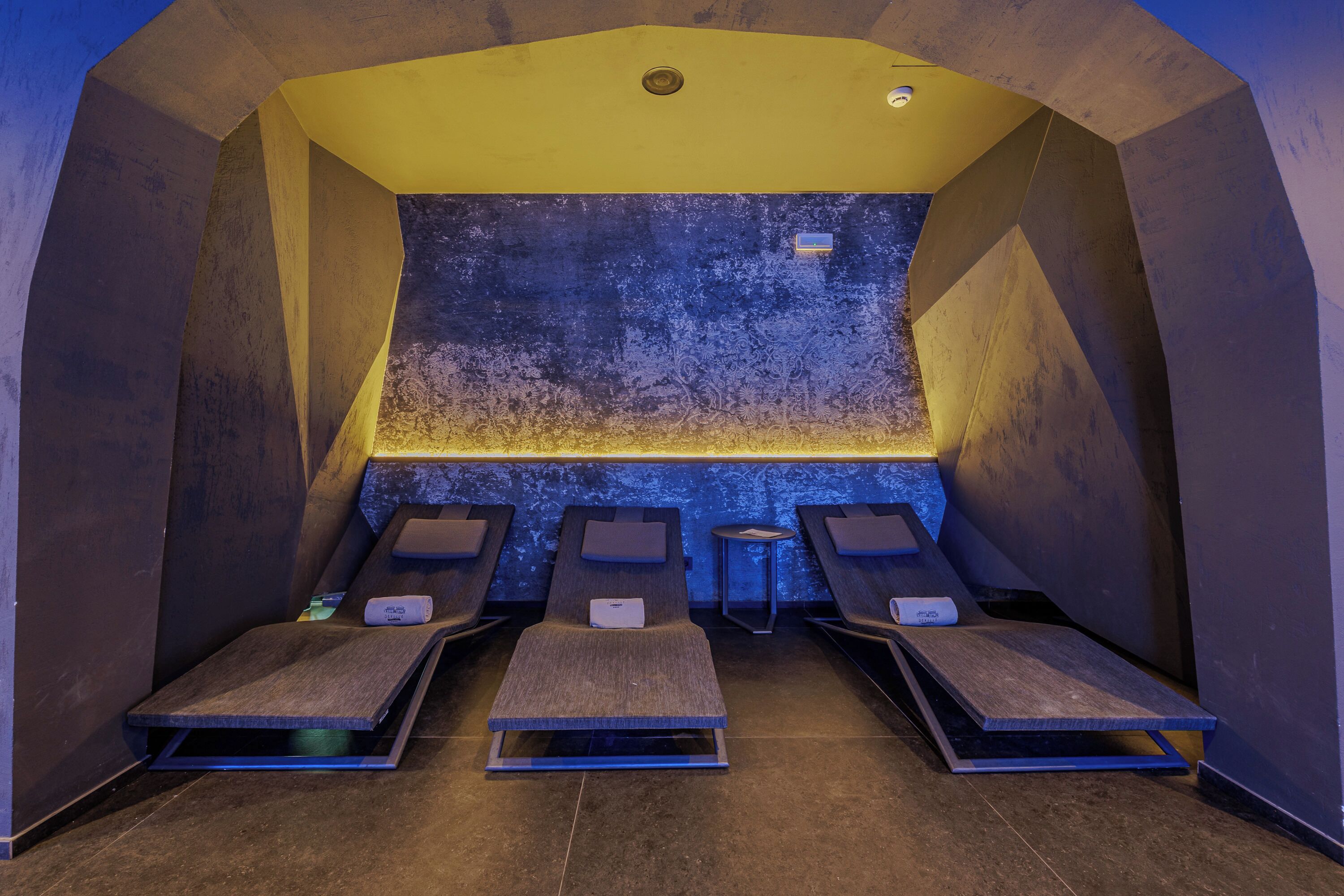 A sauna room with four benches, a textured wall, and a yellow ceiling.