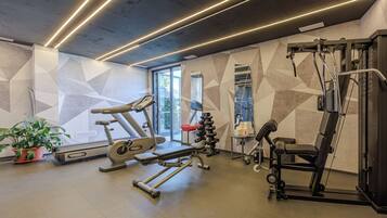 A modern gym with exercise equipment, a large window, and geometric wall patterns.