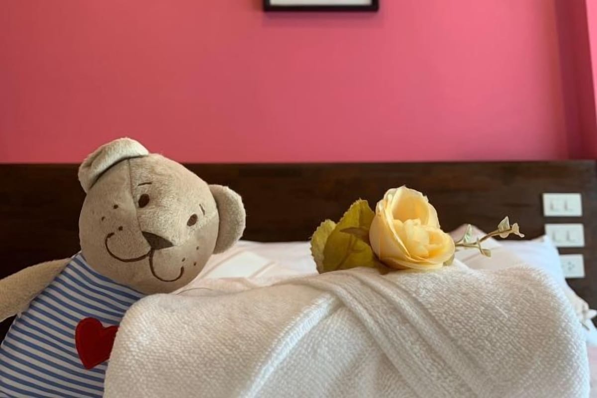 A bed with a teddy bear and a bouquet of flowers.