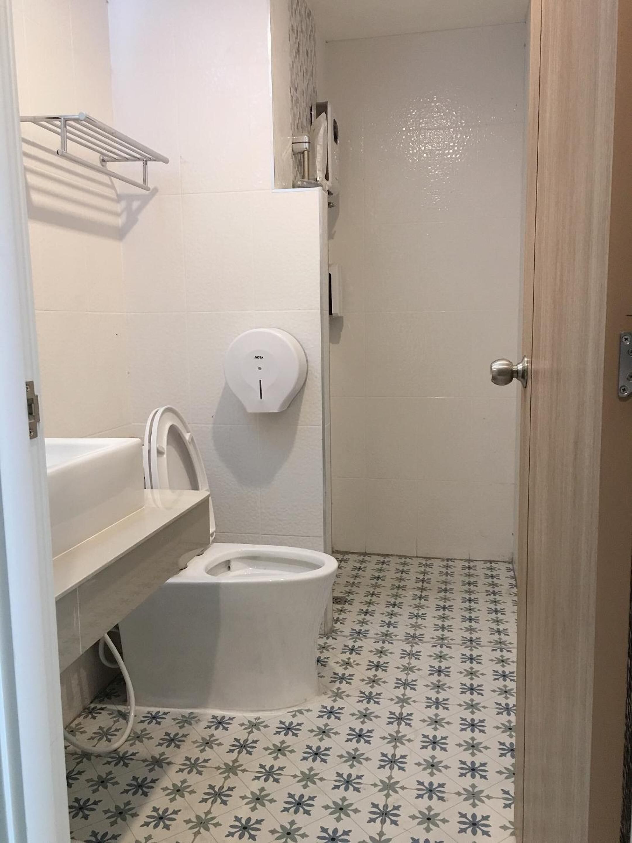 A small bathroom with a toilet, a sink, and a hand dryer.