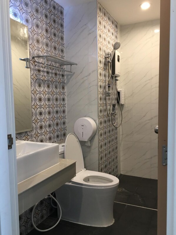 A bathroom with a toilet, a sink, a mirror, a shower, and patterned walls.