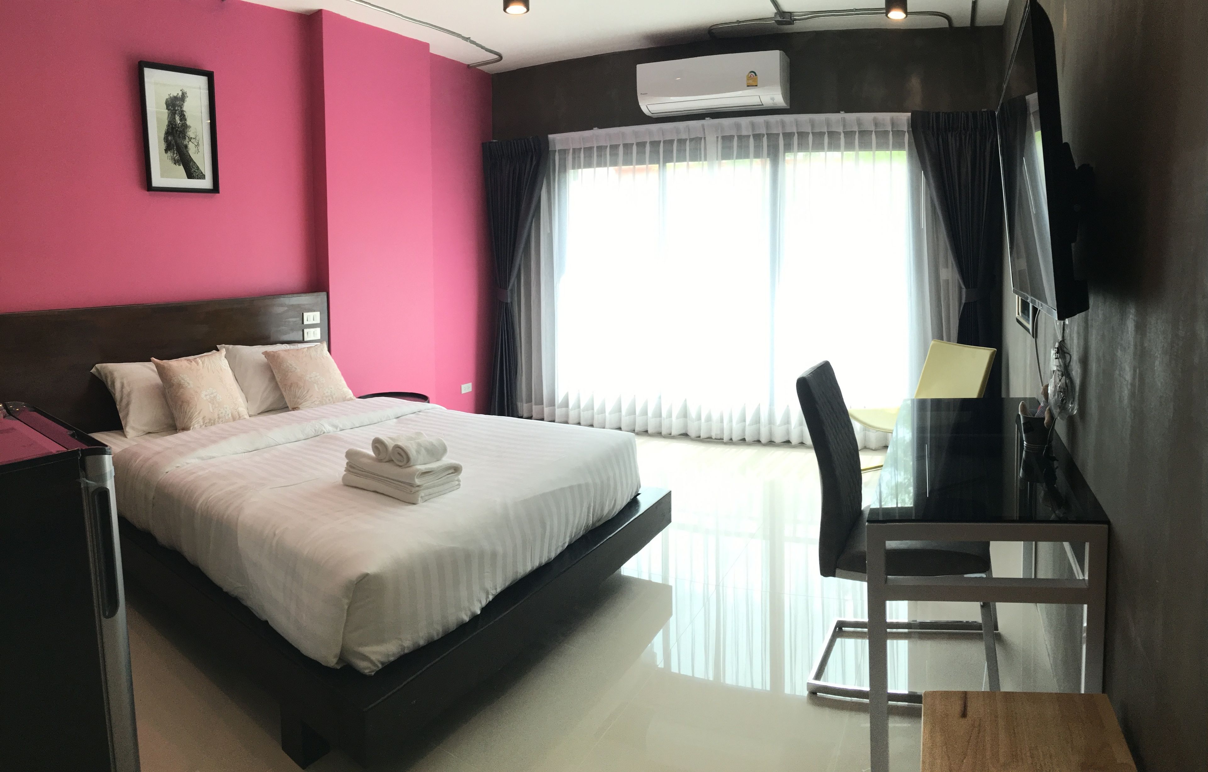 A modern hotel room with a large bed, a desk, and a TV.
