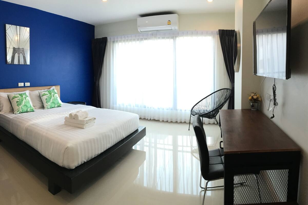 A hotel room with a bed, a desk, and a chair.