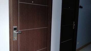 Un couloir avec deux portes, dont l’une est surmontée d’un panneau indiquant un numéro, et un sol carrelé.