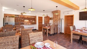 Un comedor amplio con sillas de mimbre y una mesa de madera dispuesta para una comida.
