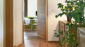 Un pasillo con piso de madera y un comedor al fondo.