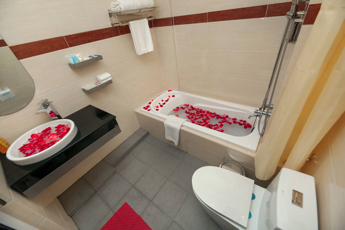 Un baño con una bañera llena de pétalos de rosa, un lavabo y un inodoro.