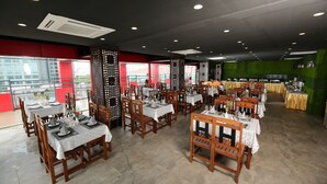 Un restaurante con varias mesas y sillas, una zona de bar y vistas a edificios.