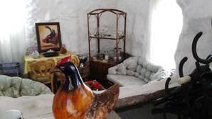 A rustic interior with a wooden rooster sculpture, a dining table with chairs, and a cushioned bench. - Lapeng Ha Mamosa (Maseru)