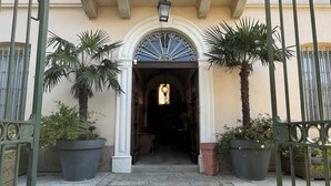 Una entrada de edificio con un camino empedrado, un arco decorativo y plantas en macetas.