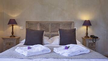 A neatly made bed with two pillows, a headboard with a lattice pattern, and two bedside tables with lamps and a phone.