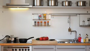 A modern kitchen with stainless steel appliances, including a Bosch oven and a range hood, and a variety of pots and pans on the wall. - Jungfrau a d Ledi by Interhome (Wengen)