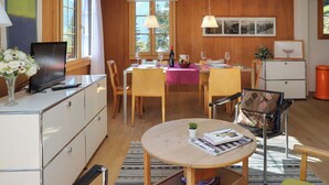 A cozy dining area with wooden furniture, a dining table set for four, and a television on a cabinet. - Jungfrau a d Ledi by Interhome (Wengen)