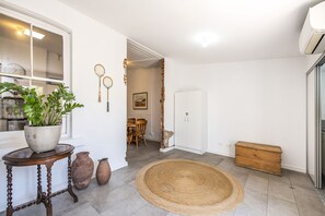 A hallway with a potted plant, a woven rug, and a wooden chest. - Central Fremantle two bedroom historic cottage (Fremantle)