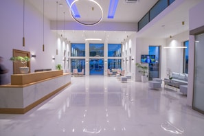 A modern hotel lobby with a reception desk, seating area, and large windows. - Imperial Palace Hotel (Rethymno)
