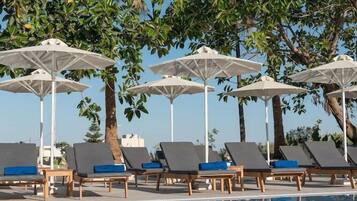 Alberca al aire libre, sombrillas en la alberca y camastros