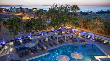 Una piscina al aire libre, sombrillas, sillones reclinables de piscina