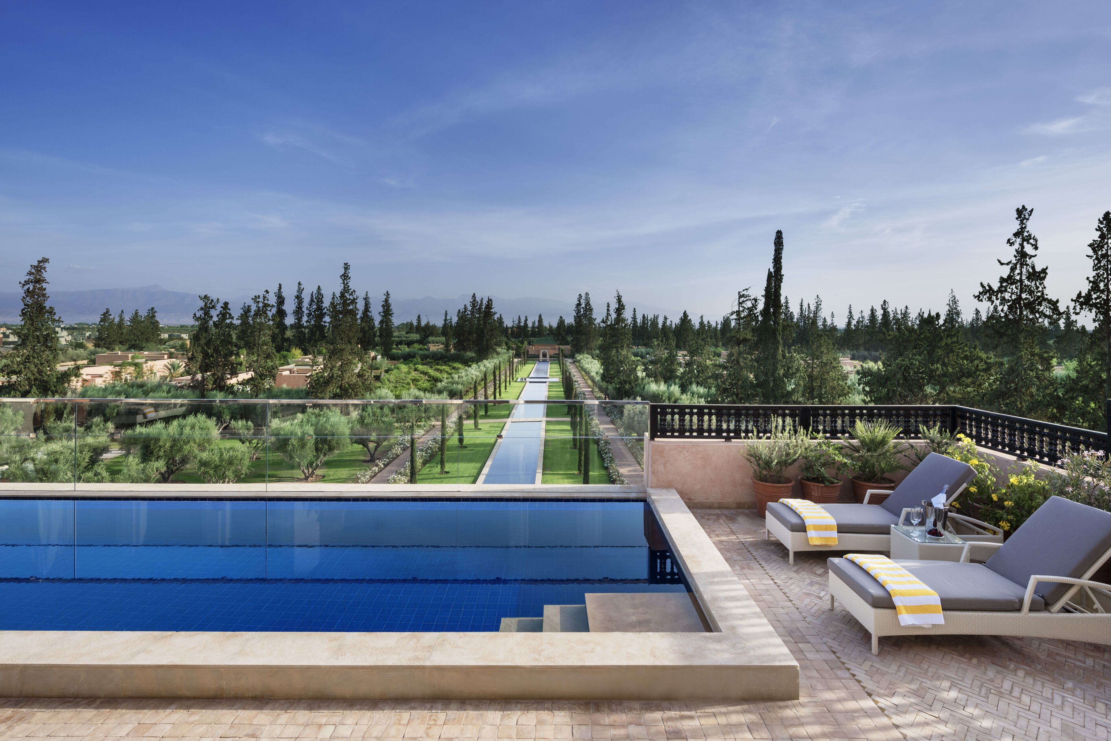 A rooftop pool area with a clear view of the surrounding landscape, including trees and distant mountains.