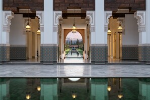 A pool area with a view of a mountain range, surrounded by ornate arches and patterned tiles. - The Oberoi Marrakech (Marrakech)