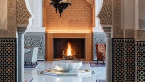 Un vestíbulo con una gran araña ornamentada, una chimenea y detalles de azulejos intrincados.