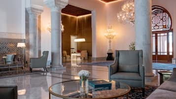 A spacious lobby with marble columns, a grand chandelier, and comfortable seating areas.