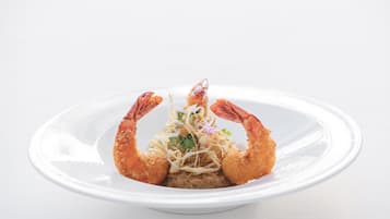 A plate with a dish featuring two large, golden-brown prawns and a central garnish.