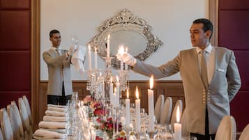 A formal dining table set with candles, flowers, and a mirror above it.