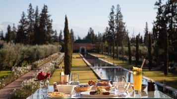 Una mesa servida con comida y bebidas, con vistas a un jardín y un sendero.