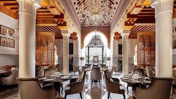 A luxurious dining area with ornate chandeliers, high ceilings, and intricate woodwork.