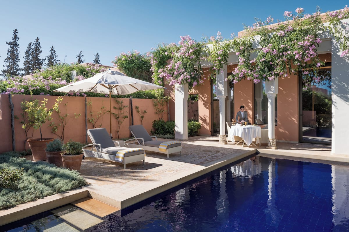 Ein Poolbereich mit Liegestühlen, einem Tisch und einer Pergola mit blühendem Efeu.